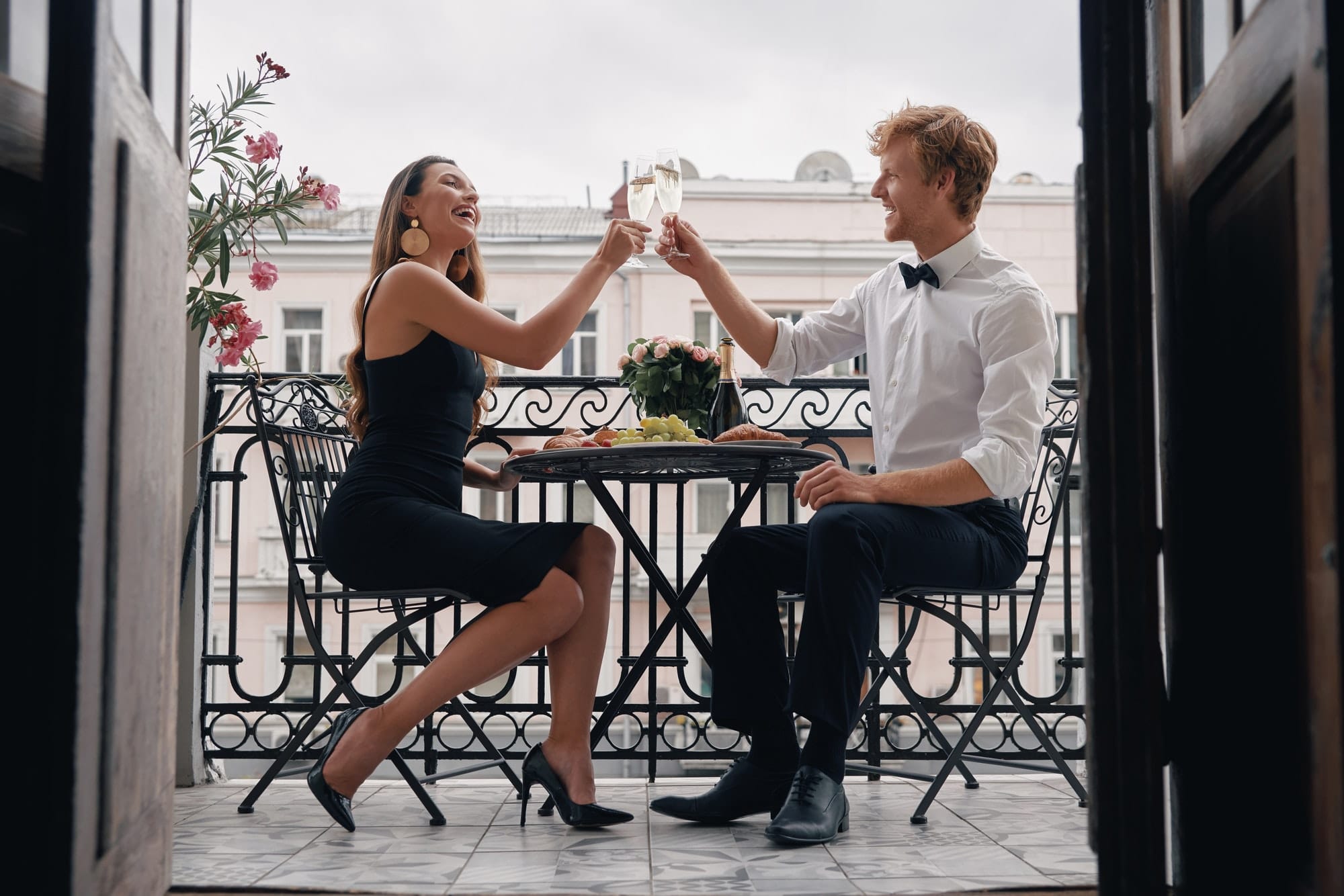 Happy loving couple toasting with champagne while having a romantic dinner on the balcony
